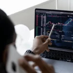 Person analyzing stock market graphs on a laptop screen.