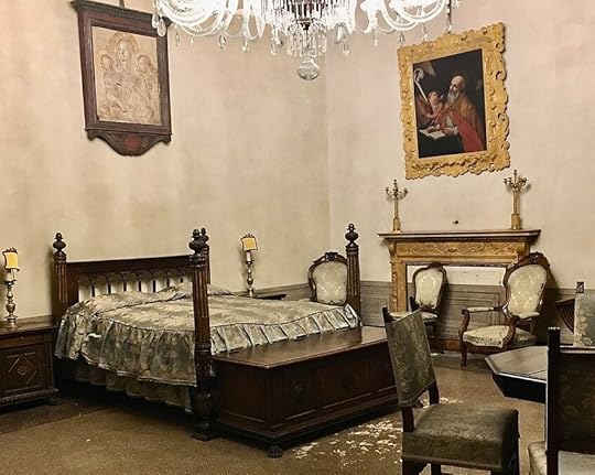 Photograph in the same room in Palazzo Medici, focusing on the large four-poster bed, wider than it is long, built of dark wood with a large chest at the foot of the bed for storage. Around it chairs are gathered, where secretaries could take dictation or visitors meet with the leaders who often used such a bed as their main office. Above the bed hangs a relief carving of the Virgin and Child with angels, and on the wall to the right a painting of Saint Jerome hard at work at his desk as an old man, with an angel helping him. Saint Jerome was a patron saint of scholars, translators, Latin-lovers, and was famous for turning his back on comforts and embracing pain and mortification of the flesh as a way of urging himself to focus on his work and service to the Lord and humanity. The angel helper makes me think of Angelo Poliziano, the famous Homeric poet and dear friend of Lorenzo who often took dictation for him in this room when Lorenzo couldn't lift a pen.