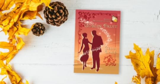 Copy of Goblin Fruit lying on a white wood desk, surrounded by golden yellow leaves and pinecorns that highlight the yellow in the cover.