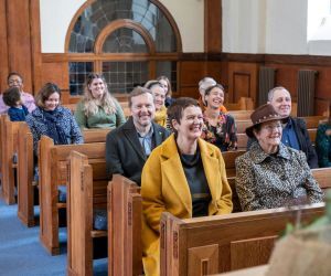 People smiling as they listen to a eulogy