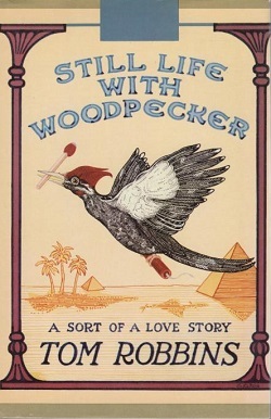 Still life with woodpecker cover by Tom Robbins. Desert scene with a Pileated Woodpecker carrying a match in its beak.