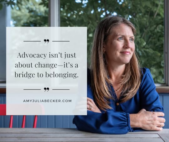 Amy Julia sits at a wooden table and looks off into the distance. Text overlay says: “Advocacy isn’t just about change—it’s a bridge to belonging.”