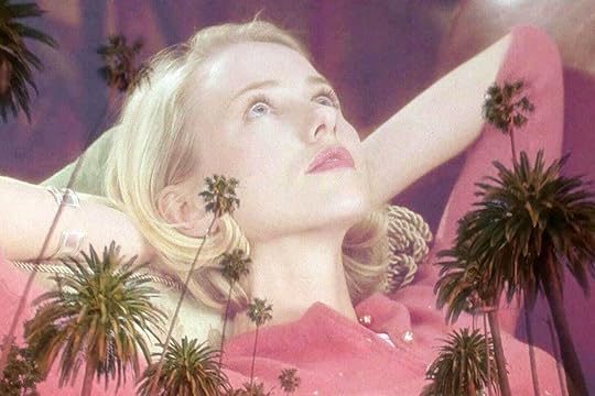Naomi Watts reclines in a pink cardigan, her body superimposed over a Los Angeles sunset, in