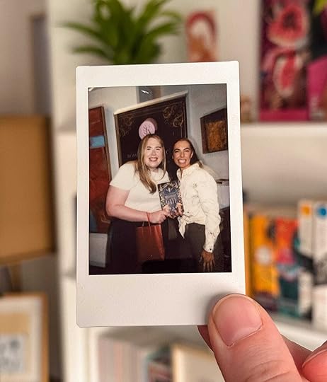 Polaroid picture of two women. MG Hunt is on the left and SK Stapar is on the right. MG Hunt is holding the book 'Midnight Gate'.