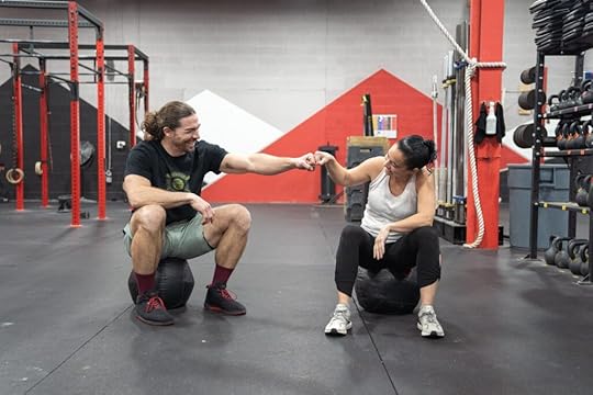 Two happy clients exchange a fist bump in a gym.