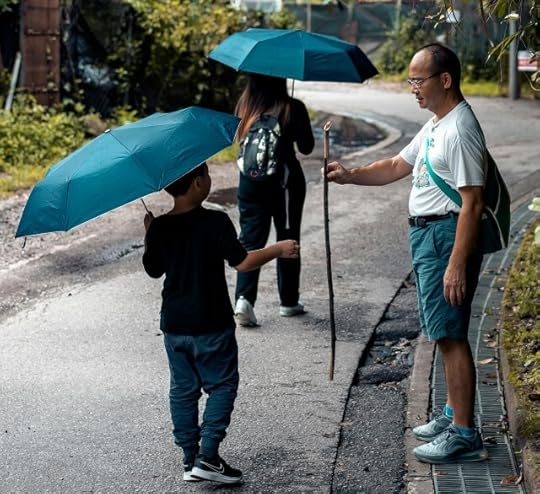 Three people, two with umbrellas and one without. Not caring is not not caring.