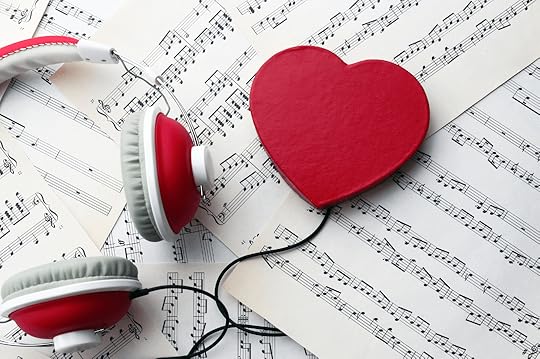 A pair of red and white headphones, a red heart-shaped object, and scattered sheet music pages, symbolizing love for music.
