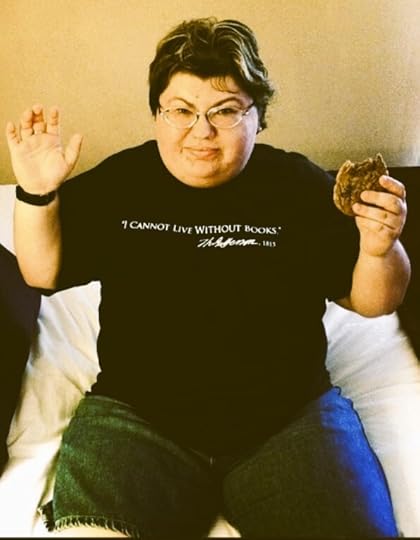 author photo in colour of a plus size woman with glasses and short hair in a black t-shirt that reads