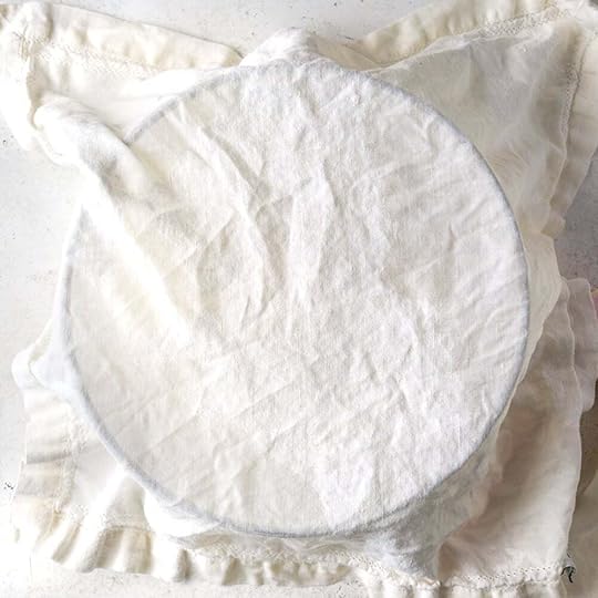 A damp kitchen towel over a bowl filled with focaccia dough.