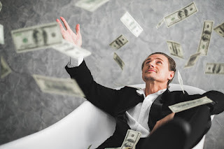 skinny white dude in a tux throwing money into the air