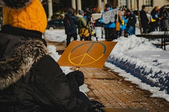 Pick Your Battles and Know Your Allies. A person holding a peace sign at a protest. 