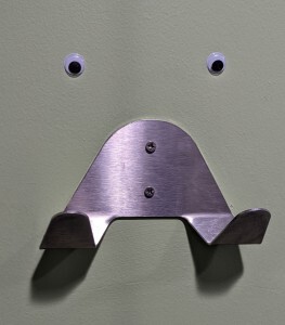 PIcture of a double metal hook with eyes stuck above it so it looks like a face with two outstretched arms.