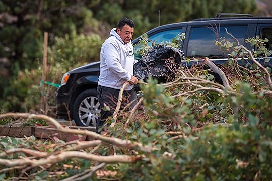 A man clears downed trees near his house in Seaside...