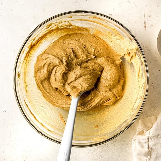 Brown cookie dough in a bowl on a white surface.