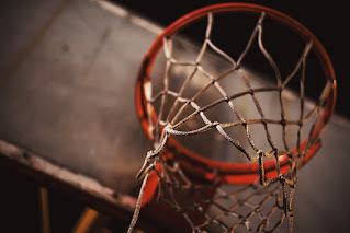 Image from underneath a basketball hoop (orange rim and gray net)