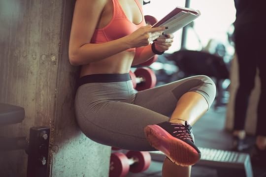 Fitness coach/personal trainer reading in a gym