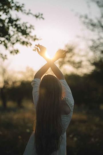 Current image: young woman standing on the meadow stretching her arms towards rising sun