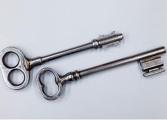 Two long, old fashioned silver keys laid side by side.