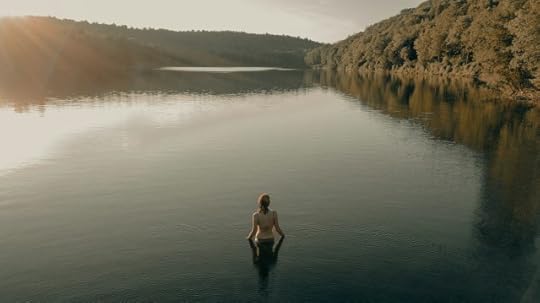 Woman in a river looking across the water. Your sanity is found via mindfulness.