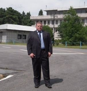 A man wearing a suit with buildings in the background