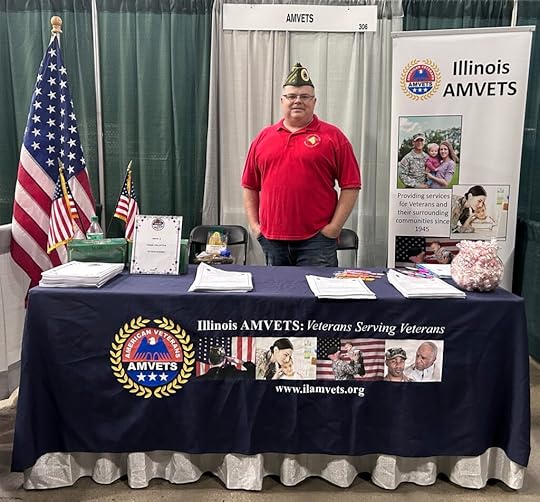 Man in red shirt standing at an AMVETS display table