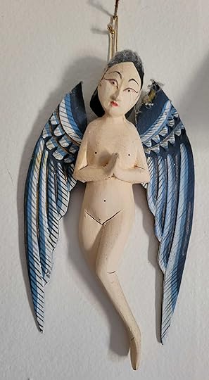 A wooden Balinese Angel hanging on a wall