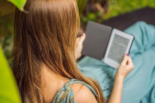 Woman reads e-book on deck chair in the garden.