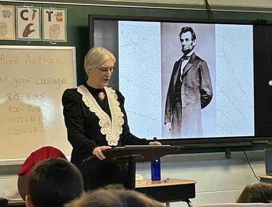 Woman dressed as Susan B. Anthony with students and image of Abraham Lincoln