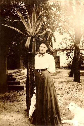 Young woman in long skirt with a white blouse on her estate in Russia in the Nineteenth Century. She stands by a palm tree with a white dog at her feet.