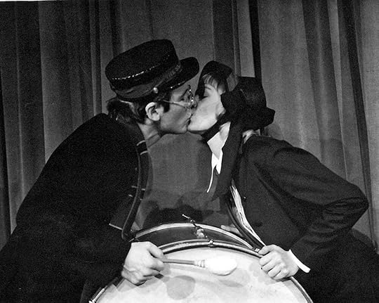 Young man and woman wearing costumes and kissing over a large drum.