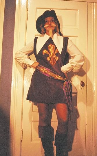 Young woman dressed in a Musketeer costume with a large white collar and boots and floppy hat.