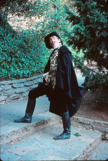 Actor in a Renaissance costume with a cape and sword making a funny face and over acting.