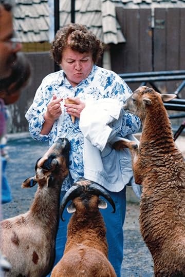 Older woman trying to feed greedy goats.