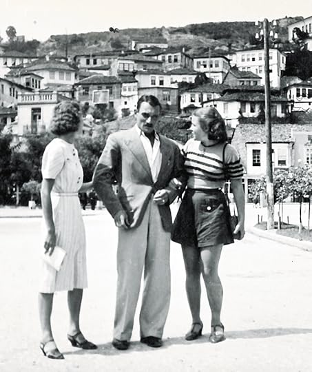 handsome man with two young women on a street with old village in background