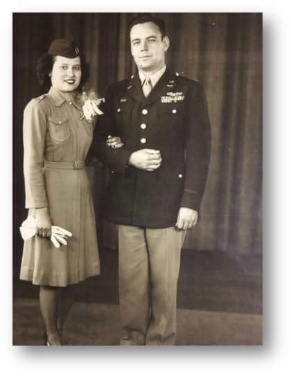 A vintage black-and-white photograph of a man and woman standing side by side, dressed in formal military attire. The man is wearing a decorated military uniform with medals and insignia, including a pilot's wings, and light-colored trousers. His arm is linked with the woman, who is wearing a belted military-style dress with a floral corsage pinned to her chest, gloves in one hand, and a matching hat. The background features a plain curtain.