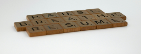 Close up of flat wooden blocks with letters that spell out PAUSE BREATHE RESUME