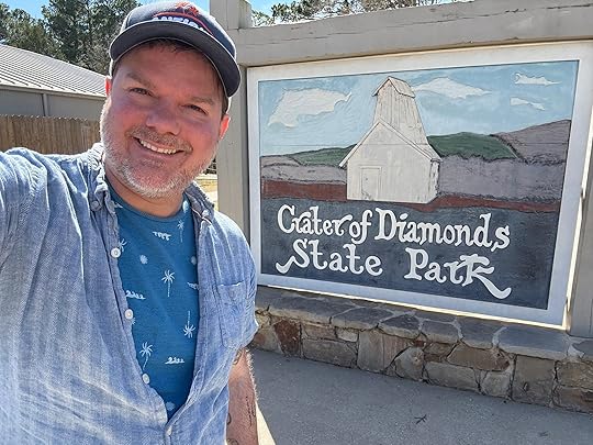 a man smiling in front of a sign