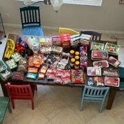 groceries laid out on dining table with chairs scattered.