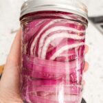 Marie holding up a jar of pickled onions made from her Quick Pickled Red Onion Recipe