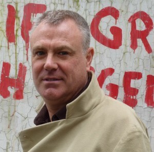 headshot of Stephen Oram against graffitied urban wall