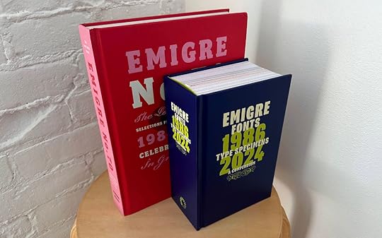 Two books standing upright in three-quarter view on a stool. The larger red book in back is Emigre No. 70, the smaller thicker blue book in front is Emigre Fonts: Type Specimens, 1986–2024.
