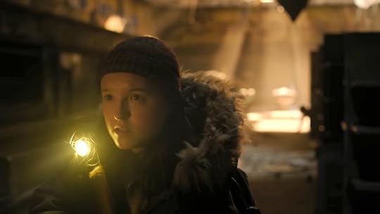 Ellie with a flashlight as a stalker far away crawls on the floor behind her on The Last of Us