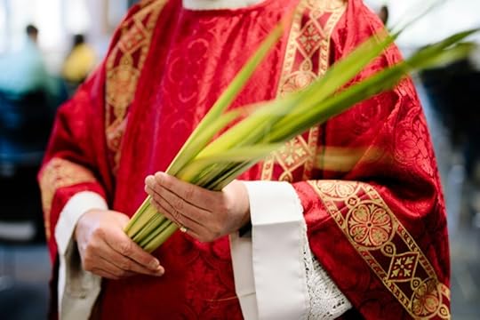 Traditional priest in red robes holding a green palm leaf