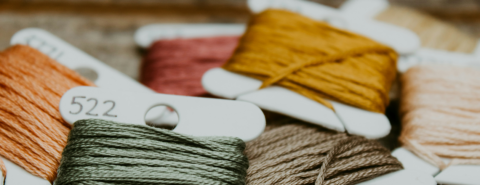 Close up of green and yellow embroidery thread on a brown wooden table