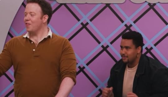 A screenshot of Dropout's "Make Some Noise" show. The screenshot shows Brennan Lee Mulligan actively speaking while Lou Wilson is crouched behind him waiting in focused anticipation..