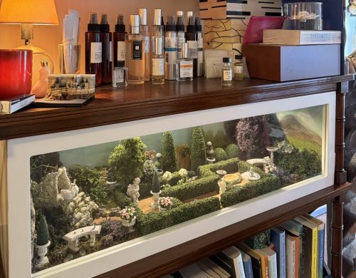 A miniature garden landscape built inside a a wooden bookshelf.
