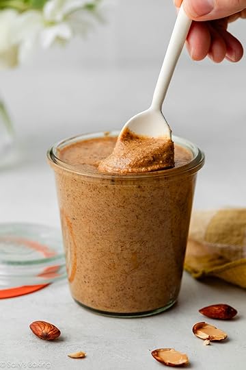 homemade almond butter in glass jar with white spoon.