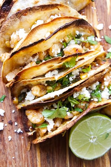 Finished toasty, cheesy shrimp tacos on a cutting board garnished with queso fresco and fresh cilantro.