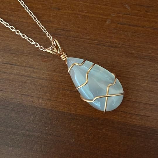 Transparent white stone pendant with a copper wire wrap and rose gold chain.