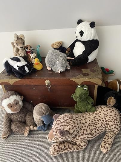 An old wood toy chest with barious stuffed animals around it.